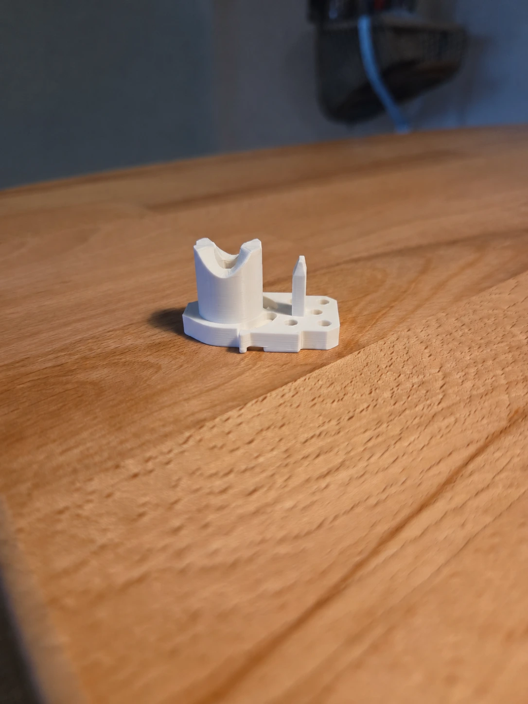 3D-gedrucktes weißes Ersatzteil für die Hotel-Duschkabine auf einer Holzoberfläche